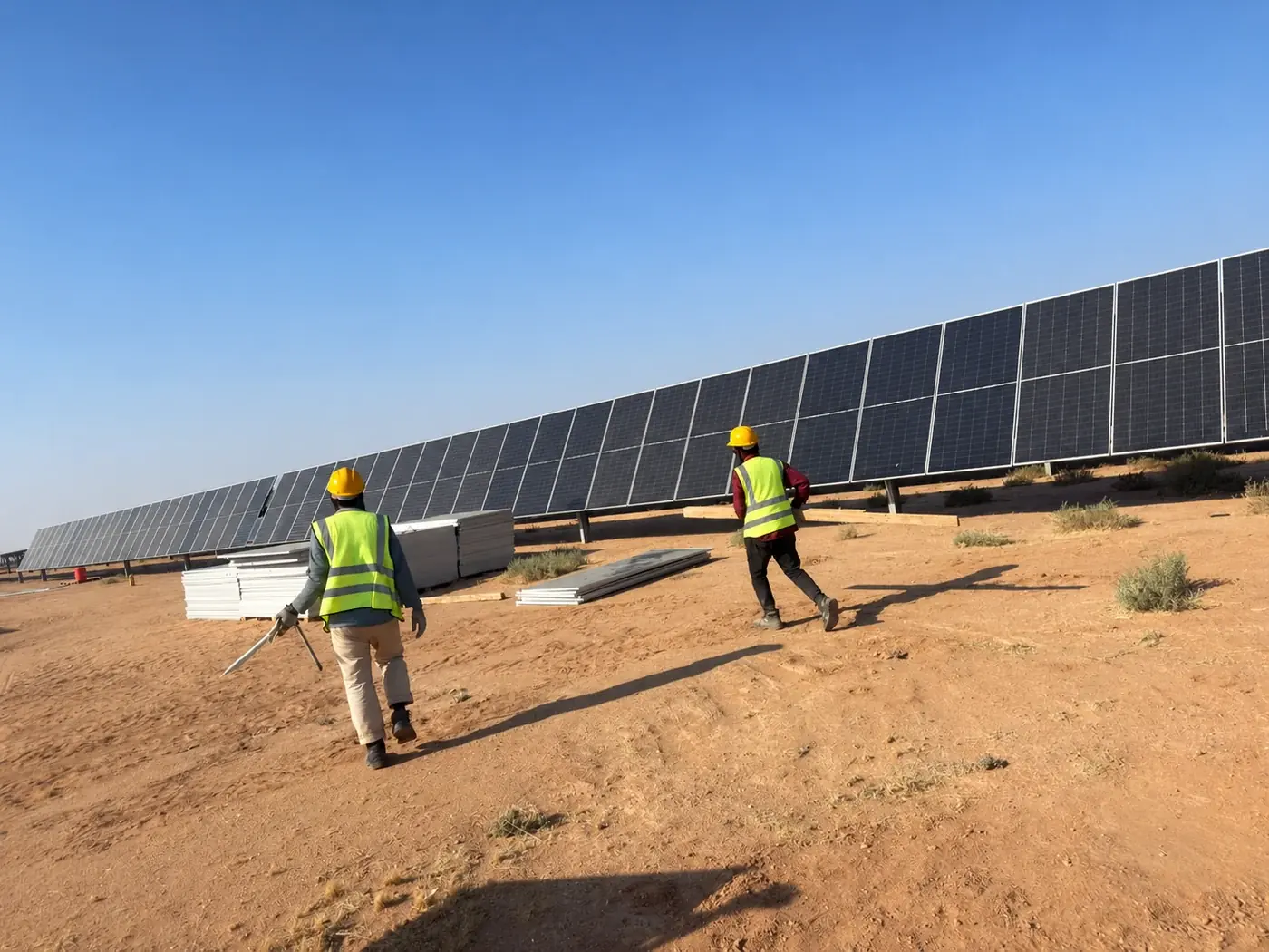 Site team walking beside solar panels, viewed from behind