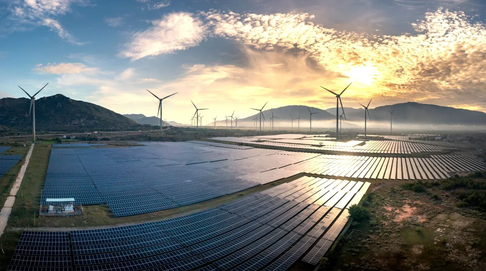 Solar panels and wind turbines at sunrise